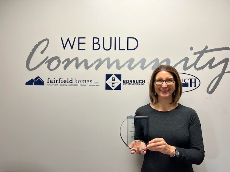 Executive holding award in front of logo wall